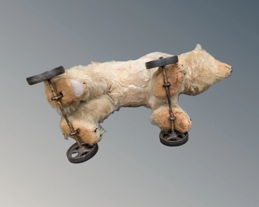 An early twentieth-century off-white mohair Steiff bear standing quadrupedally on four metal wheels. View VII