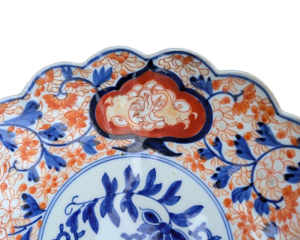 A circular Japanese Imari porcelain charger featuring a scalloped rim, hand-painted cobalt blue and iron red floral patterns, and a central botanical roundel. View III