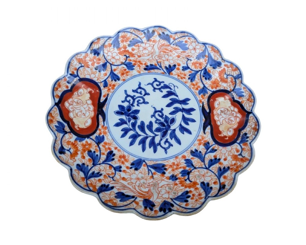 A circular Japanese Imari porcelain charger featuring a scalloped rim, hand-painted cobalt blue and iron red floral patterns, and a central botanical roundel. View IV
