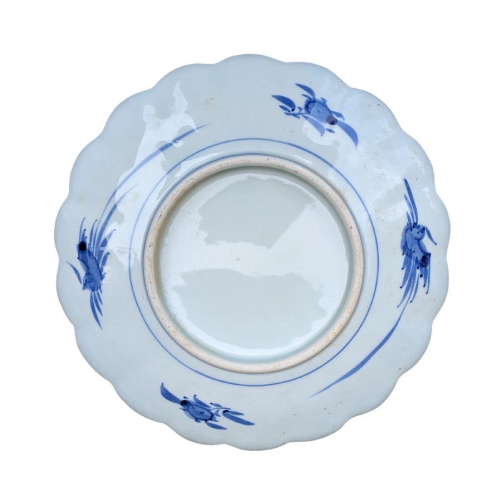 A circular Japanese Imari porcelain charger featuring a scalloped rim, hand-painted cobalt blue and iron red floral patterns, and a central botanical roundel. View V