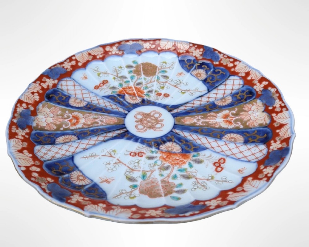 A circular Japanese Imari porcelain plate featuring a scalloped rim, fluted surface, and floral motifs in cobalt blue, iron red, and gold decoration. View II