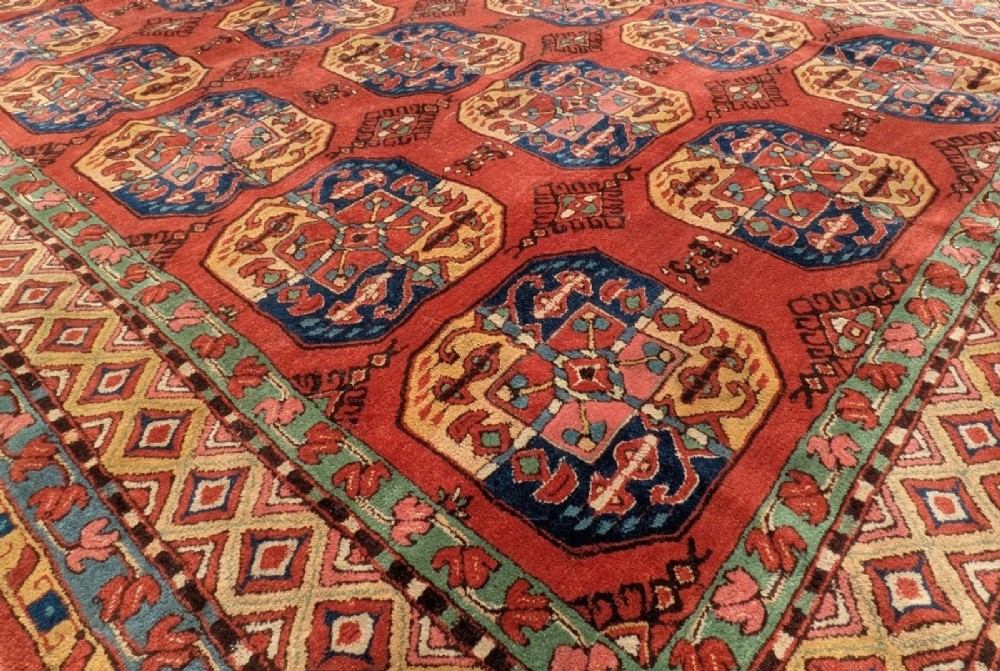 A hand-knotted rectangular wool carpet featuring repeating octagonal tribal gul motifs on a deep red field framed by geometric borders. View IV
