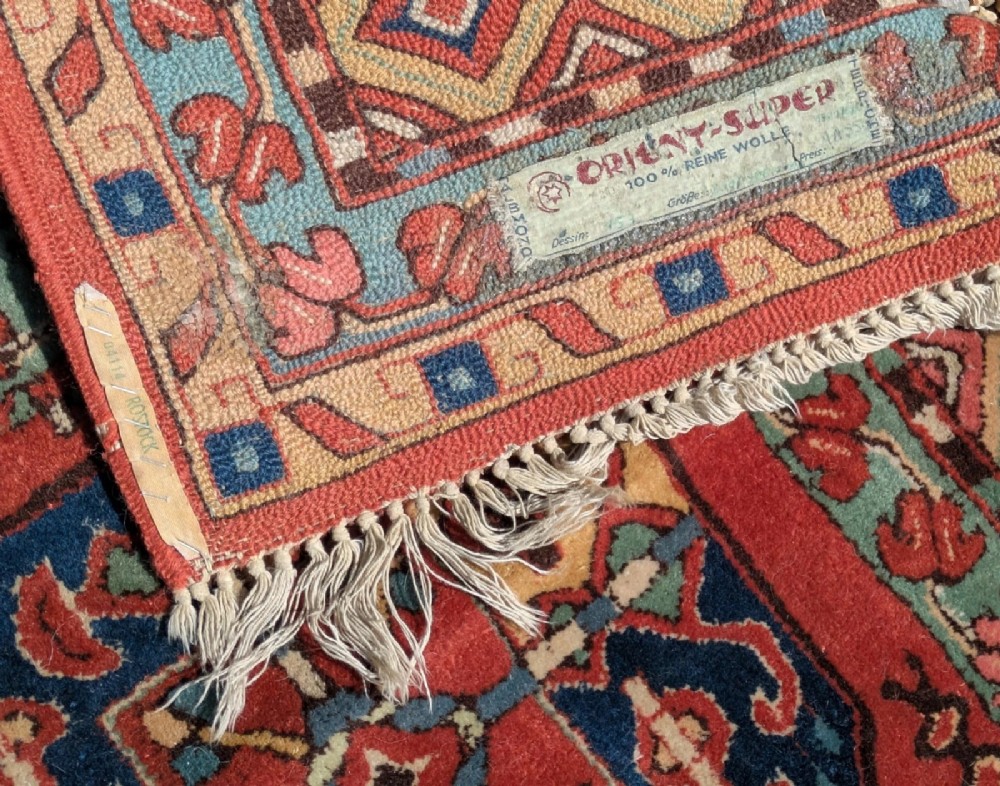 A hand-knotted rectangular wool carpet featuring repeating octagonal tribal gul motifs on a deep red field framed by geometric borders. View VI