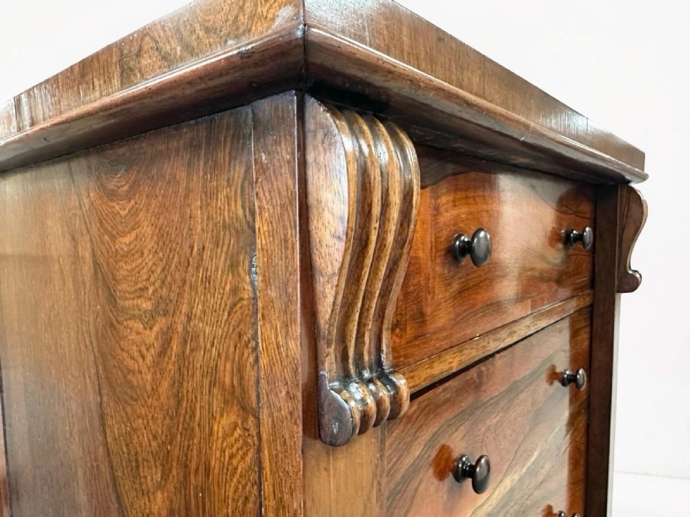 An antique Victorian rosewood Wellington chest featuring seven stacked drawers, turned wooden knobs, carved upper corbels, and a side locking bar. View IV