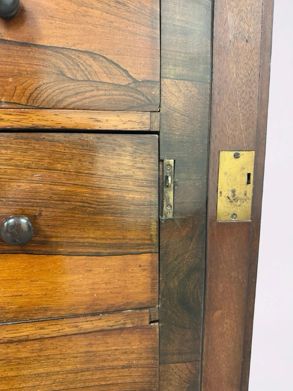 An antique Victorian rosewood Wellington chest featuring seven stacked drawers, turned wooden knobs, carved upper corbels, and a side locking bar. View VI