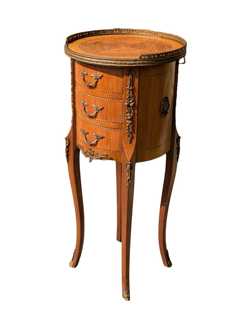 An antique circular French kingwood bedside cabinet with three drawers, geometric parquetry inlay, ornate brass mounts, and cabriole legs.