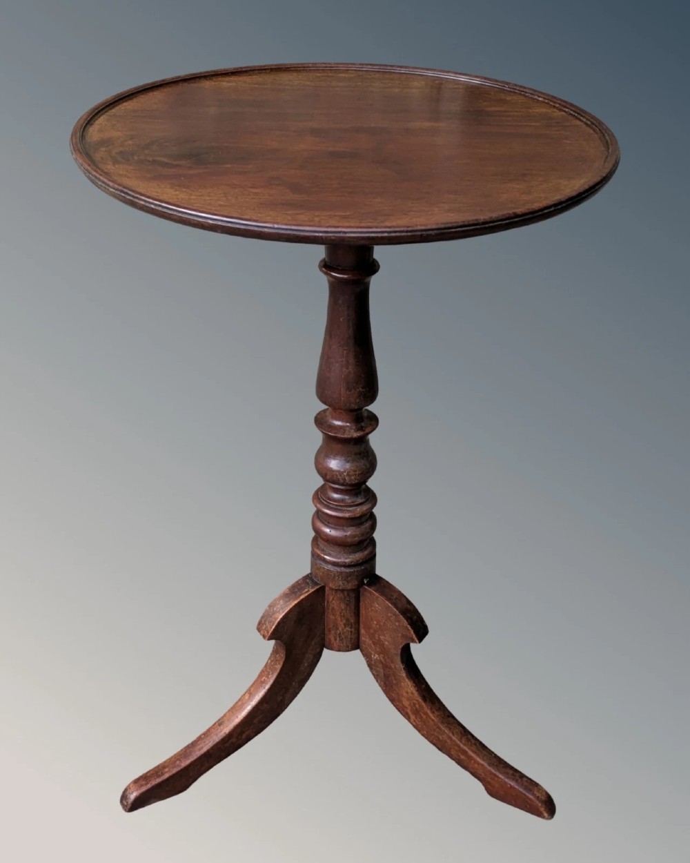 A Georgian mahogany circular tilt-top table featuring a turned central pedestal column resting on a tripod base.