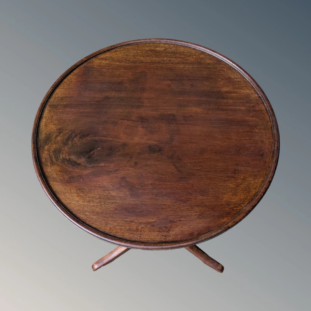 A Georgian mahogany circular tilt-top table featuring a turned central pedestal column resting on a tripod base. View V