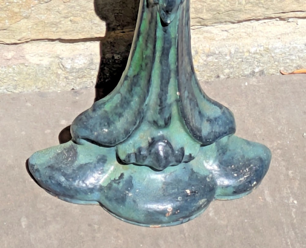 An Art Nouveau cast iron doorstop featuring a vertical stem with organic leaf motifs, a loop handle at the top, and a green patinated finish. View V