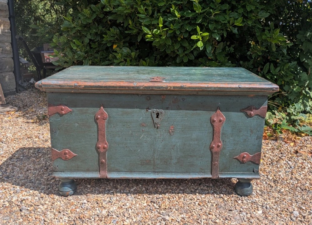 A rectangular teal blue painted pine storage chest featuring hand-forged iron strapwork, corner brackets, and turned bun feet. View II