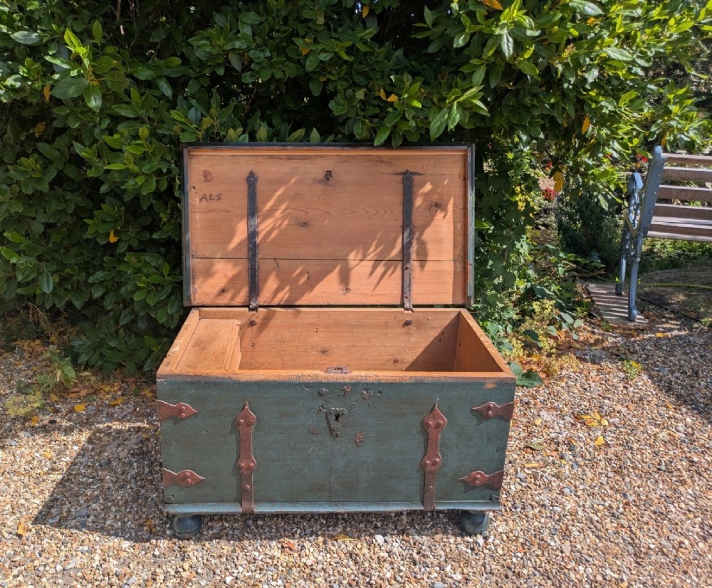 A rectangular teal blue painted pine storage chest featuring hand-forged iron strapwork, corner brackets, and turned bun feet. View V
