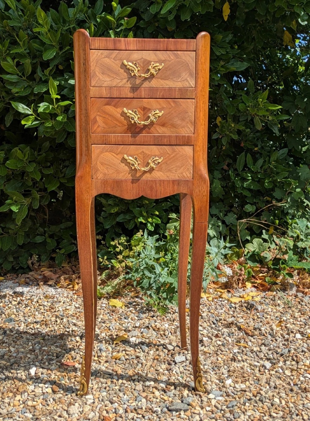 A pair of tall, slim French Louis XV style bedside cabinets crafted with geometric wood parquetry, featuring three drawers with ornate gilt handles and long cabriole legs with metal sabots. View V