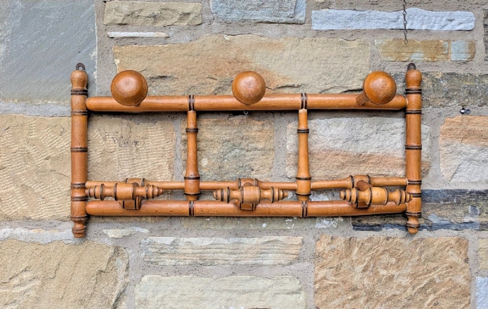 A wall-mounted wooden coat rack crafted with faux bamboo turned timber detailing and multiple spherical and lathe-turned hanging pegs. View II