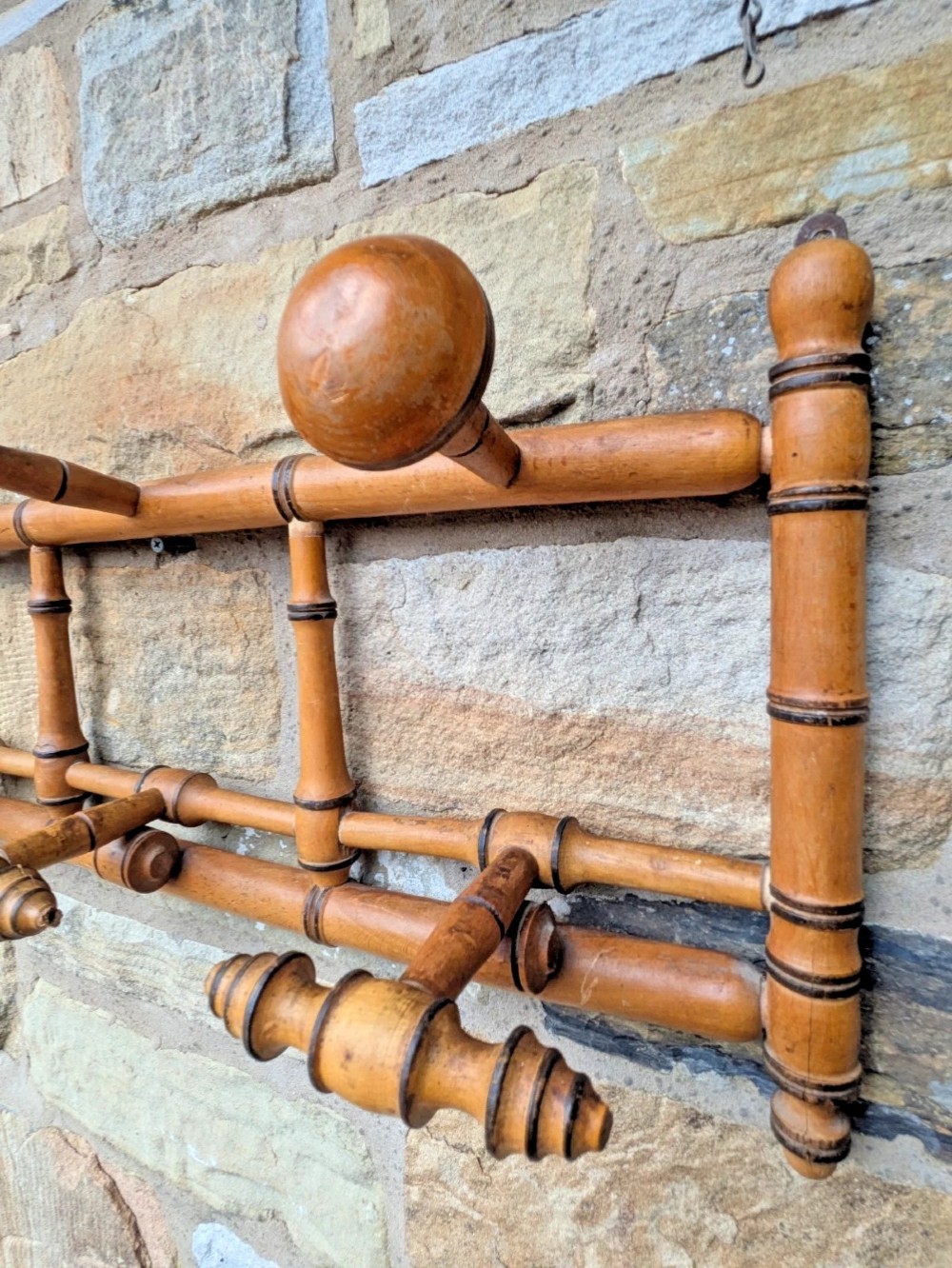 A wall-mounted wooden coat rack crafted with faux bamboo turned timber detailing and multiple spherical and lathe-turned hanging pegs. View III
