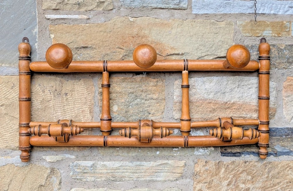 A wall-mounted wooden coat rack crafted with faux bamboo turned timber detailing and multiple spherical and lathe-turned hanging pegs. View IV