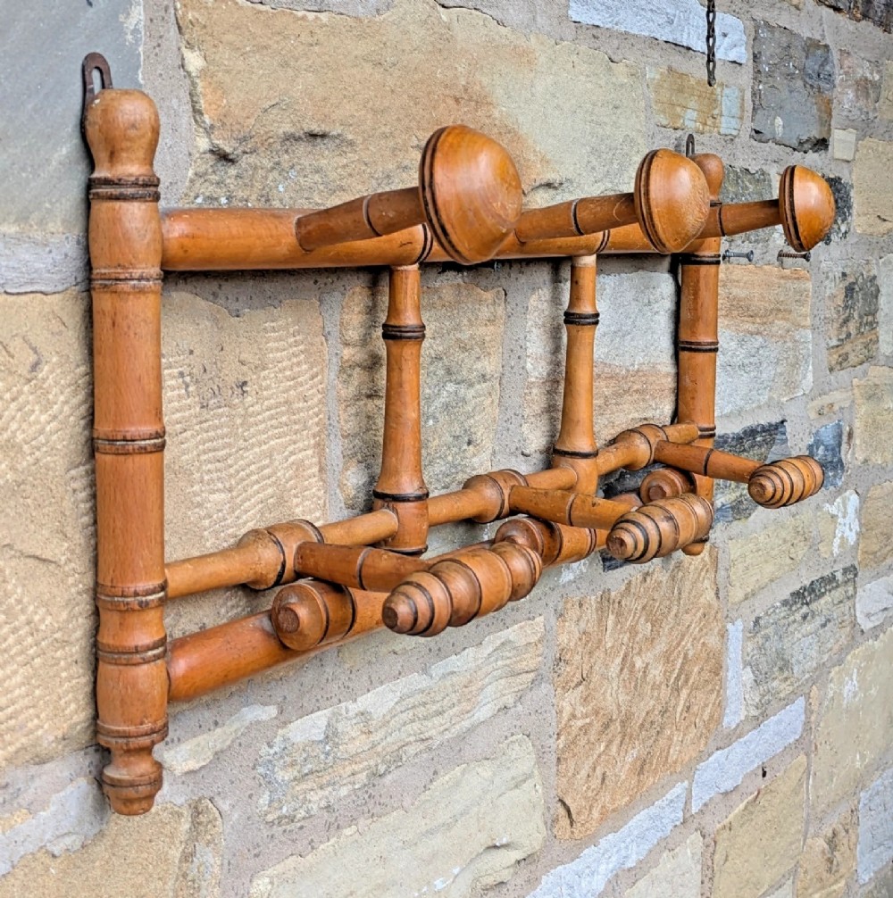 A wall-mounted wooden coat rack crafted with faux bamboo turned timber detailing and multiple spherical and lathe-turned hanging pegs. View V
