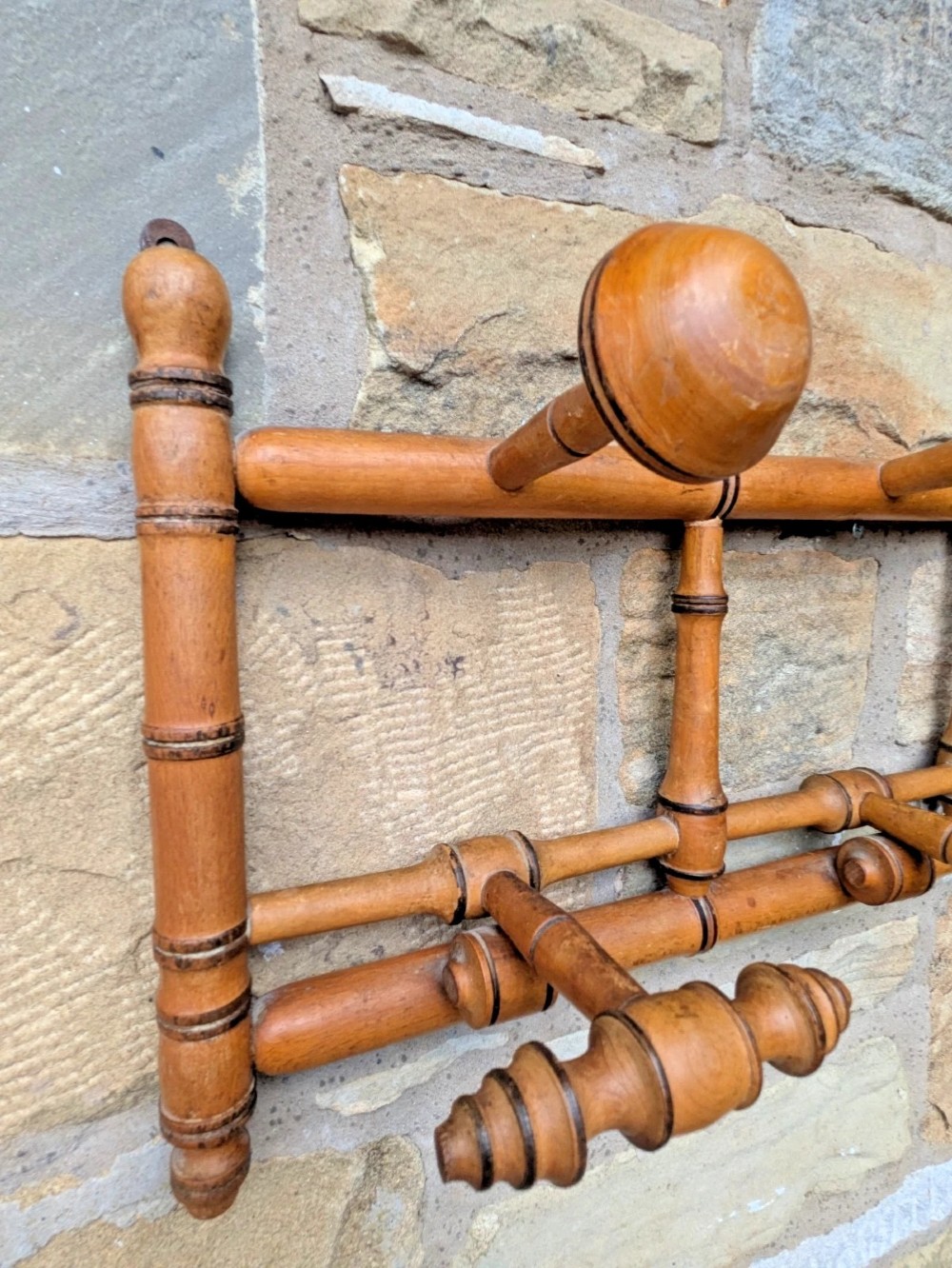 A wall-mounted wooden coat rack crafted with faux bamboo turned timber detailing and multiple spherical and lathe-turned hanging pegs. View VI