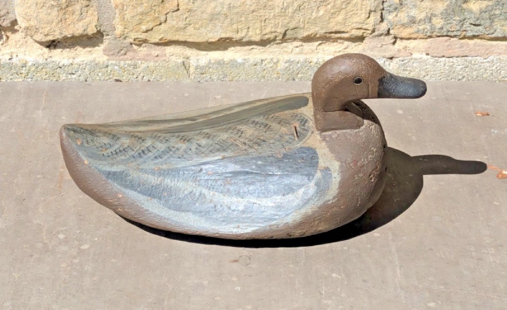 A hand-carved wooden decoy duck painted in earthy brown and grey tones with subtle feather detailing. View II