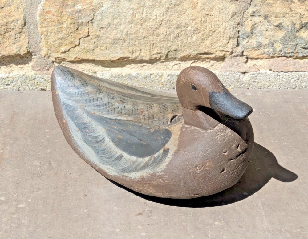 A hand-carved wooden decoy duck painted in earthy brown and grey tones with subtle feather detailing. View III