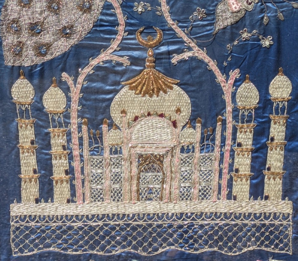 A framed vertical silk textile panel displaying metallic thread zardozi embroidery of peacocks, flowers, and the Taj Mahal on a cobalt blue ground. View III