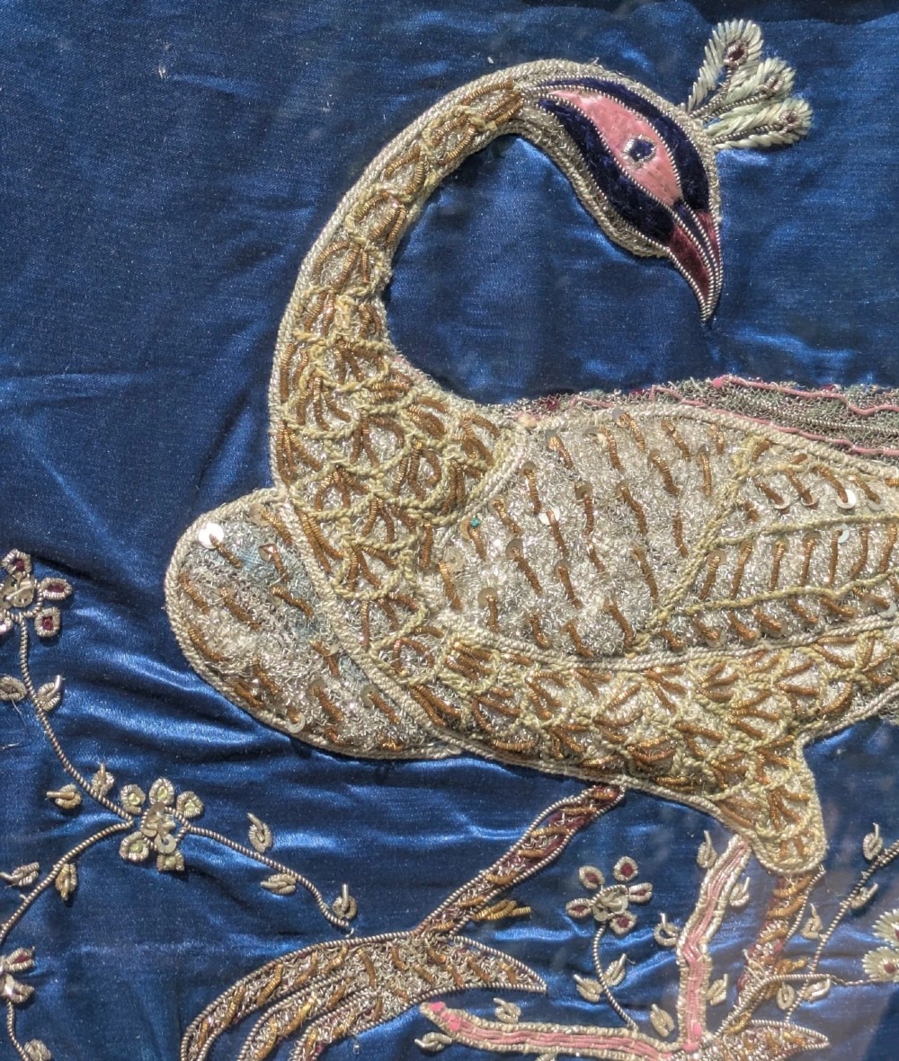 A framed vertical silk textile panel displaying metallic thread zardozi embroidery of peacocks, flowers, and the Taj Mahal on a cobalt blue ground. View VI