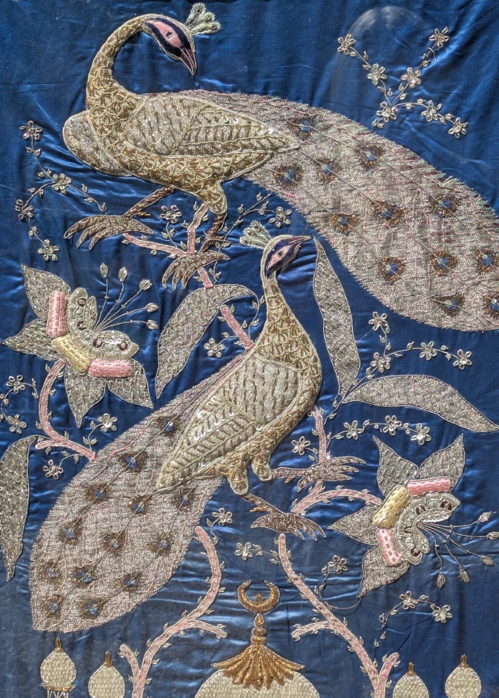 A framed vertical silk textile panel displaying metallic thread zardozi embroidery of peacocks, flowers, and the Taj Mahal on a cobalt blue ground. View VIII