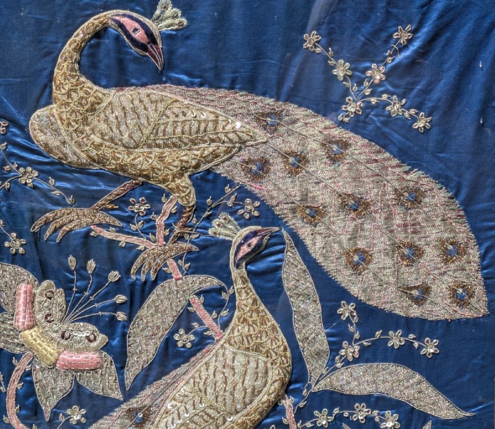 A framed vertical silk textile panel displaying metallic thread zardozi embroidery of peacocks, flowers, and the Taj Mahal on a cobalt blue ground. View IX