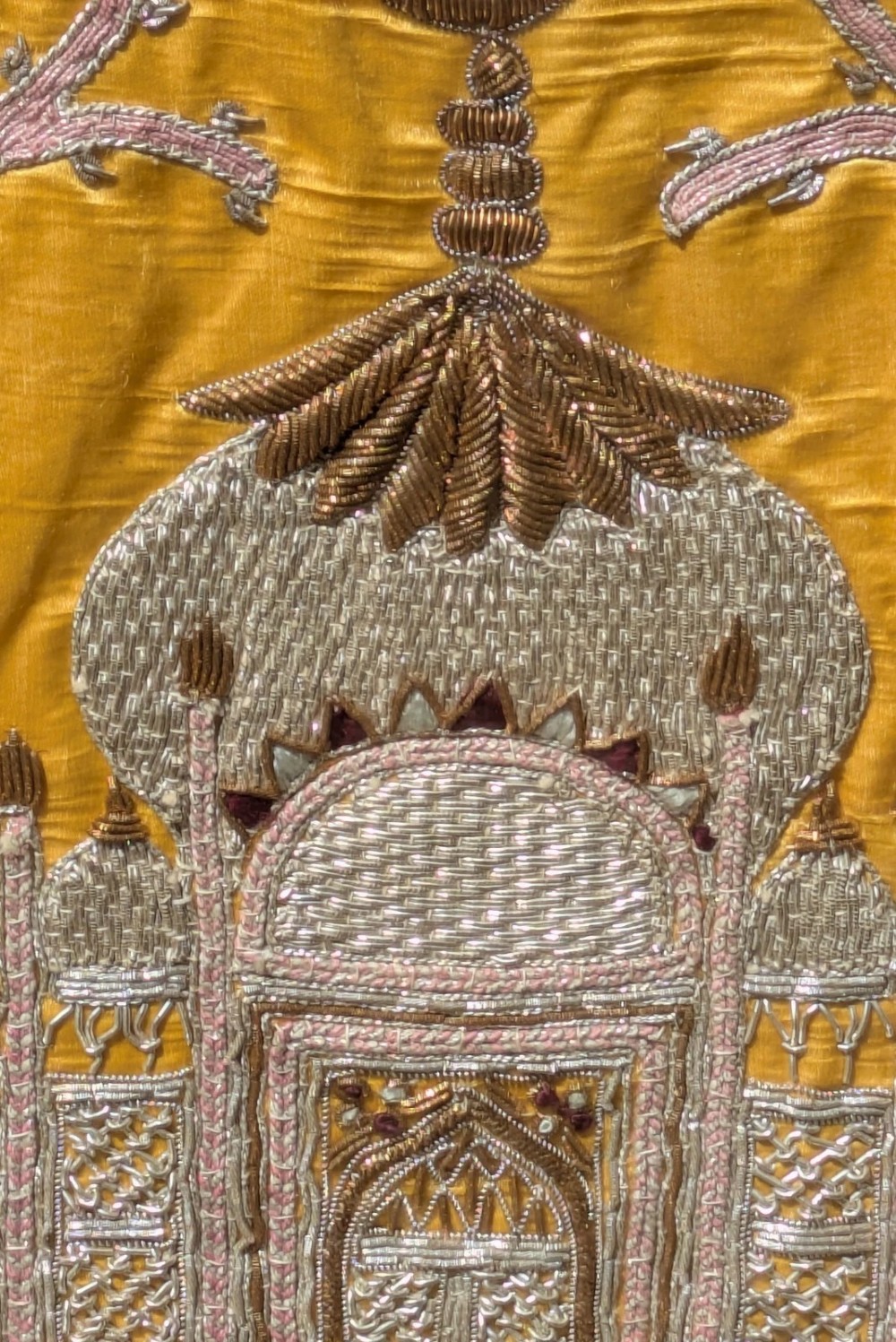 Framed vertical yellow silk panel embroidered with two peacocks, floral motifs, and an architectural depiction of the Taj Mahal in metallic thread. View IX