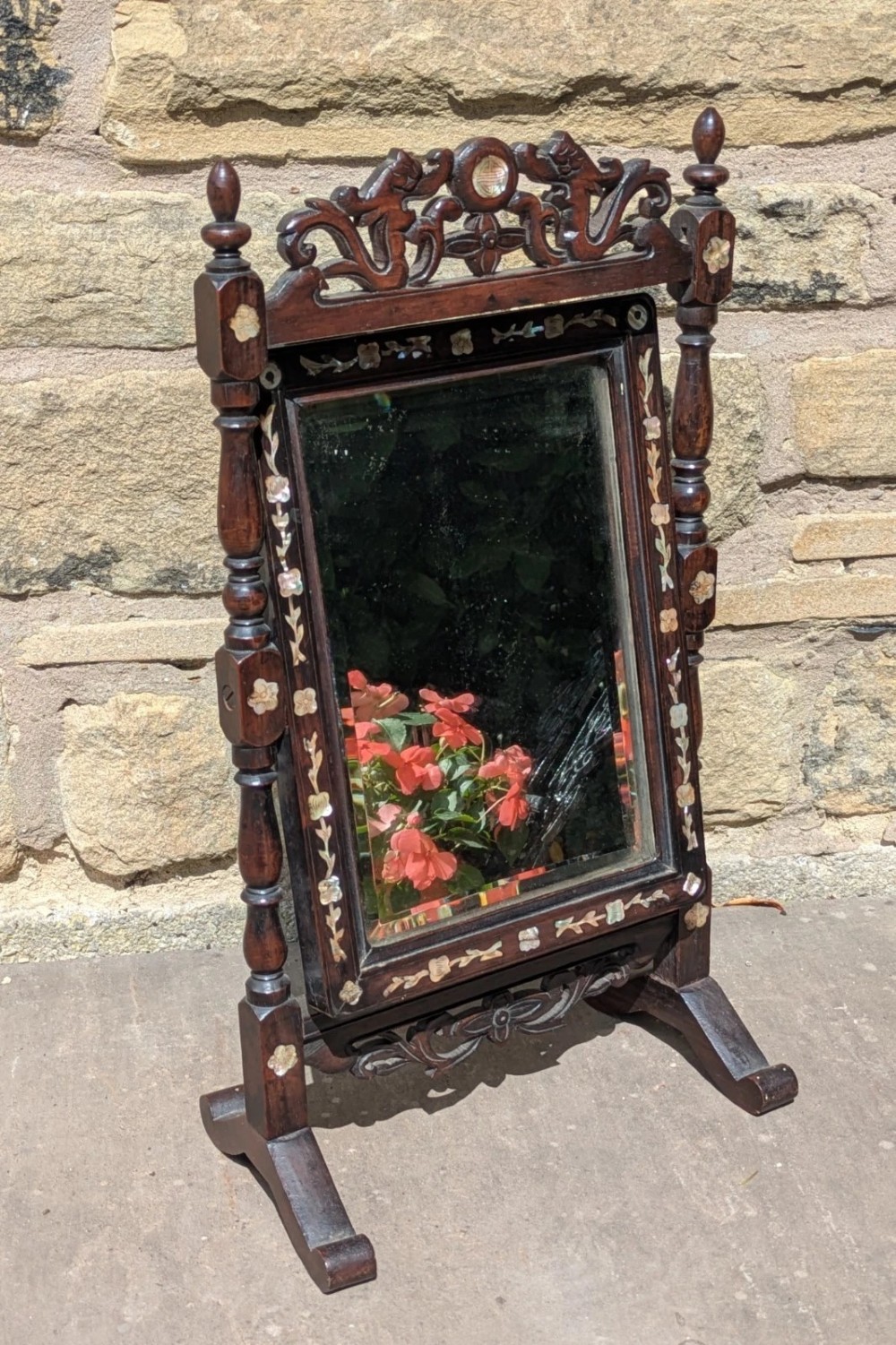A dark hardwood tabletop cheval mirror featuring floral mother-of-pearl inlay, turned uprights, and a carved cresting top. View V