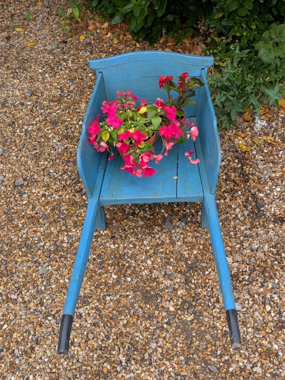 A 19th-century hand-crafted light blue painted wooden garden wheelbarrow with a spoked wheel resting on a gravel surface. View VII