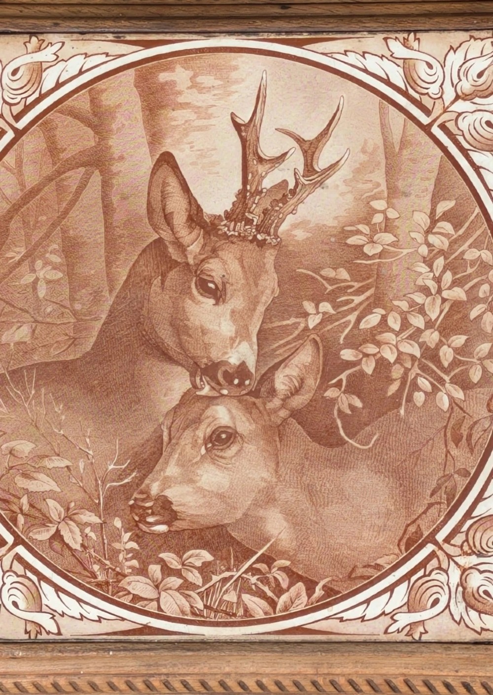 A square antique ceramic tile depicting a stag and doe in a woodland setting, framed within carved oak rope-twist moulding. View VI