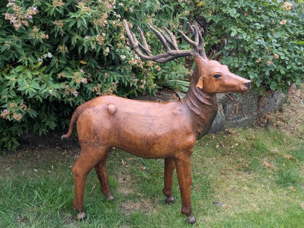 A life-like standing buck deer sculpture wrapped in warm brown stitched leather featuring large branching antlers and inset dark eyes. View IV