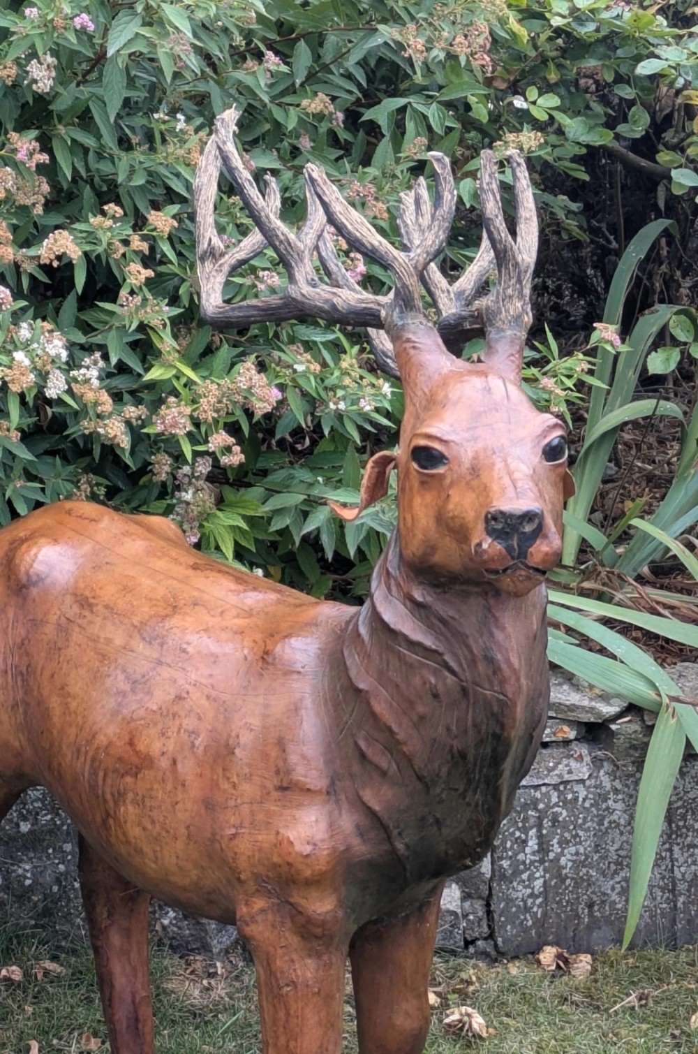 A life-like standing buck deer sculpture wrapped in warm brown stitched leather featuring large branching antlers and inset dark eyes. View V