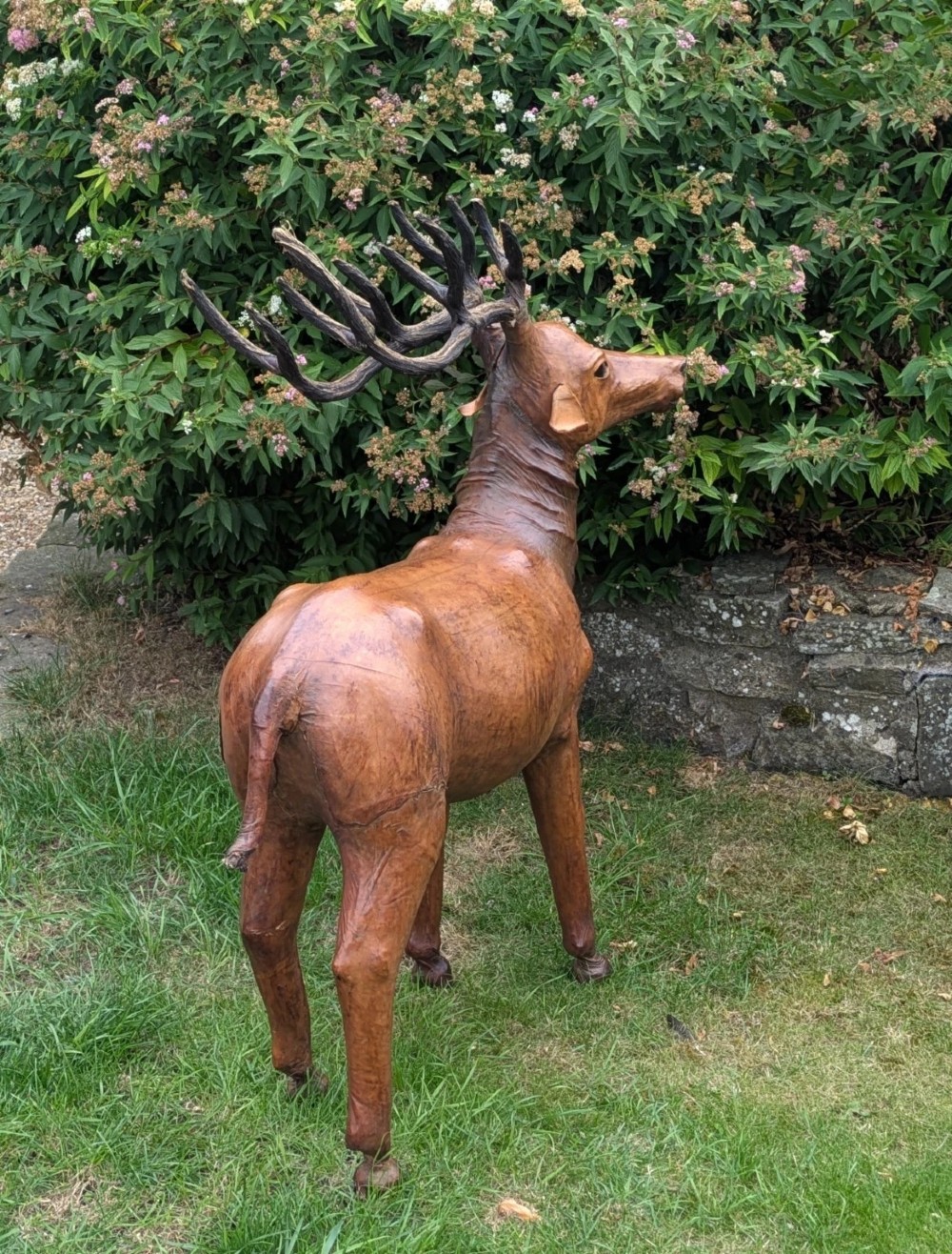 A life-like standing buck deer sculpture wrapped in warm brown stitched leather featuring large branching antlers and inset dark eyes. View VI