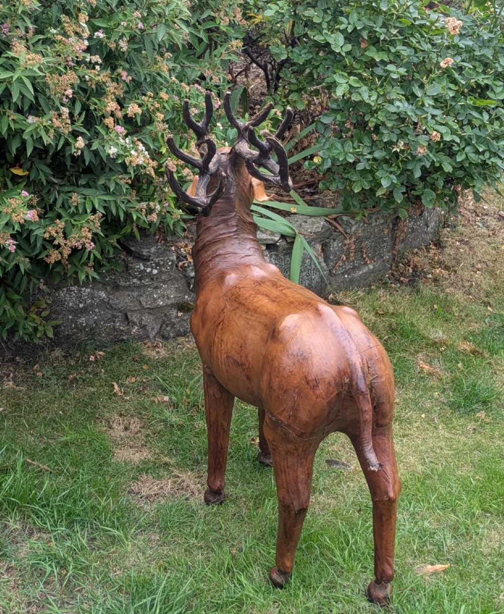 A life-like standing buck deer sculpture wrapped in warm brown stitched leather featuring large branching antlers and inset dark eyes. View VII