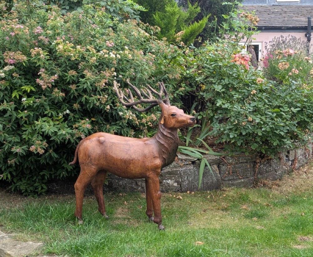 A life-like standing buck deer sculpture wrapped in warm brown stitched leather featuring large branching antlers and inset dark eyes. View VIII