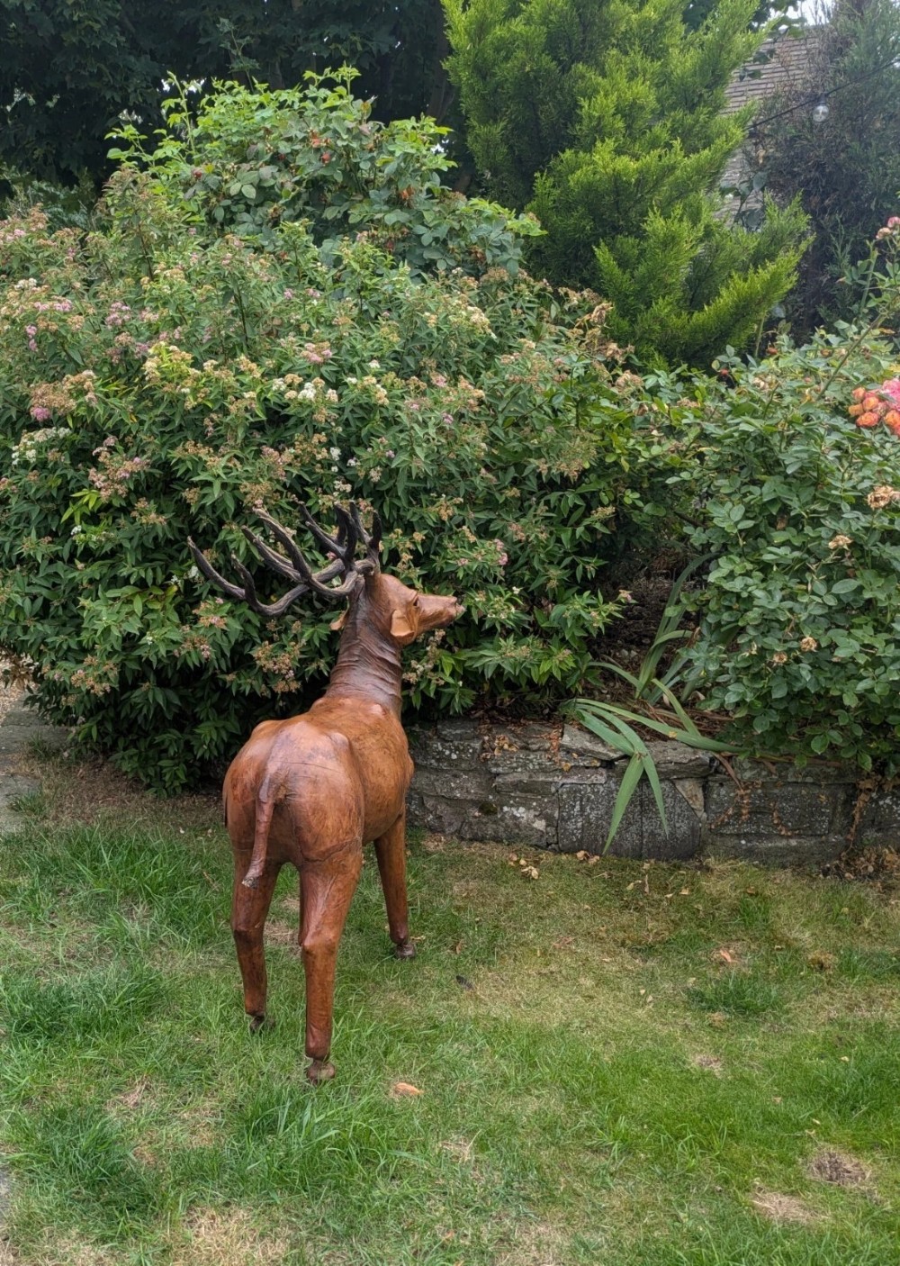 A life-like standing buck deer sculpture wrapped in warm brown stitched leather featuring large branching antlers and inset dark eyes. View IX
