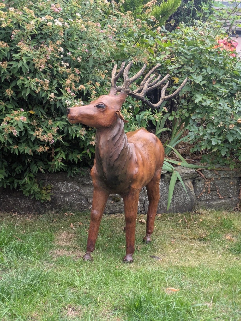 A life-like standing buck deer sculpture wrapped in warm brown stitched leather featuring large branching antlers and inset dark eyes. View XII