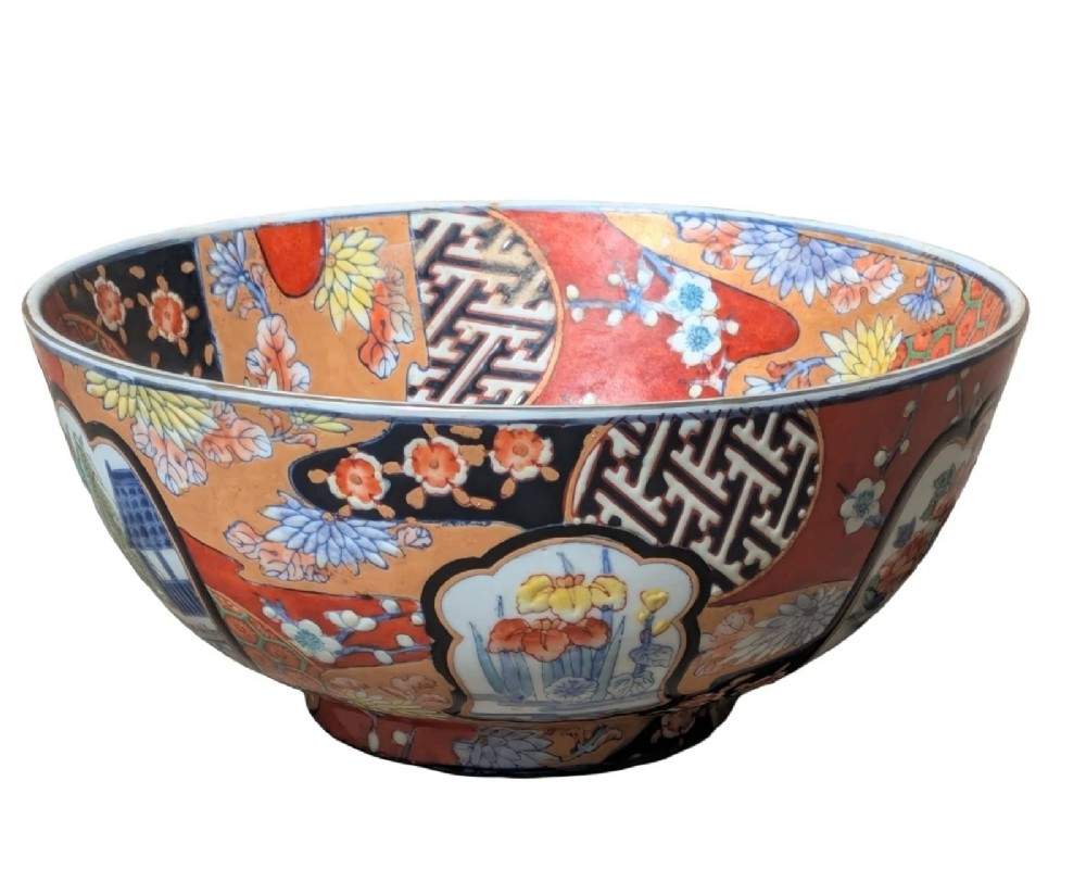 A deep round Japanese Imari porcelain bowl decorated with iron red, blue, green, and gold painted patterns featuring central figural cartouches and floral motifs. View II