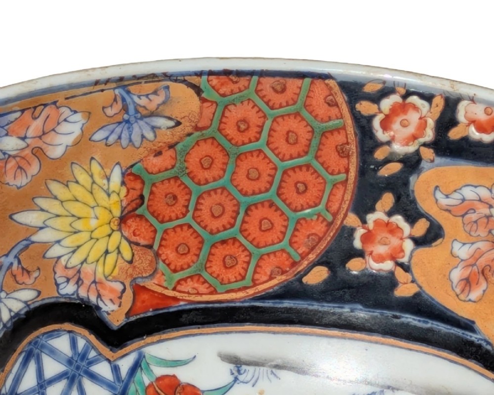 A deep round Japanese Imari porcelain bowl decorated with iron red, blue, green, and gold painted patterns featuring central figural cartouches and floral motifs. View III