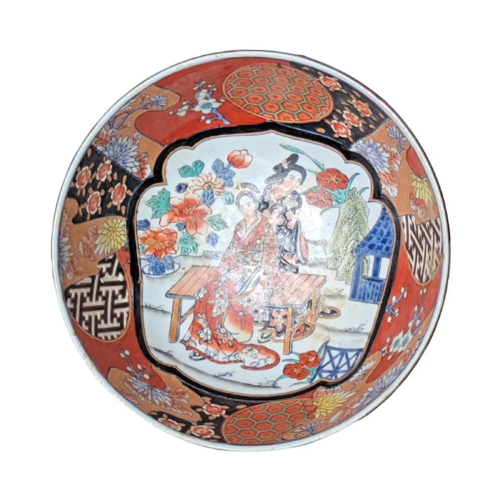 A deep round Japanese Imari porcelain bowl decorated with iron red, blue, green, and gold painted patterns featuring central figural cartouches and floral motifs. View IV