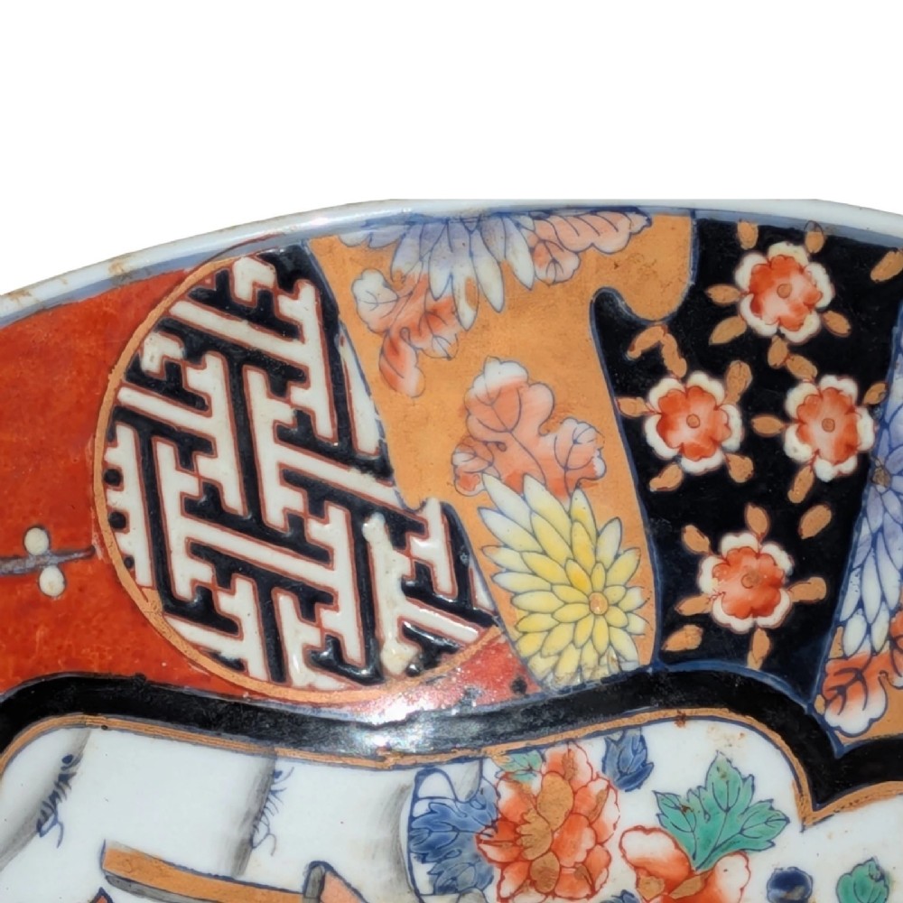 A deep round Japanese Imari porcelain bowl decorated with iron red, blue, green, and gold painted patterns featuring central figural cartouches and floral motifs. View V