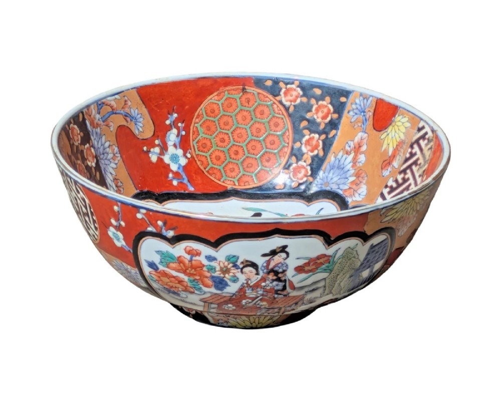 A deep round Japanese Imari porcelain bowl decorated with iron red, blue, green, and gold painted patterns featuring central figural cartouches and floral motifs. View VI