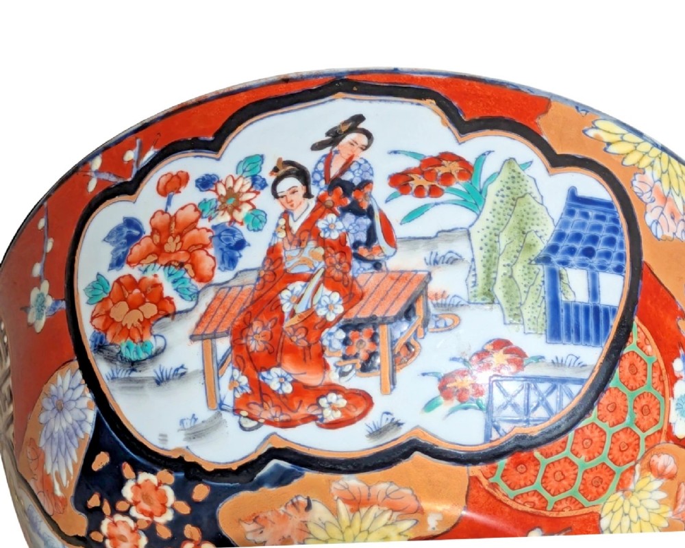 A deep round Japanese Imari porcelain bowl decorated with iron red, blue, green, and gold painted patterns featuring central figural cartouches and floral motifs. View VII