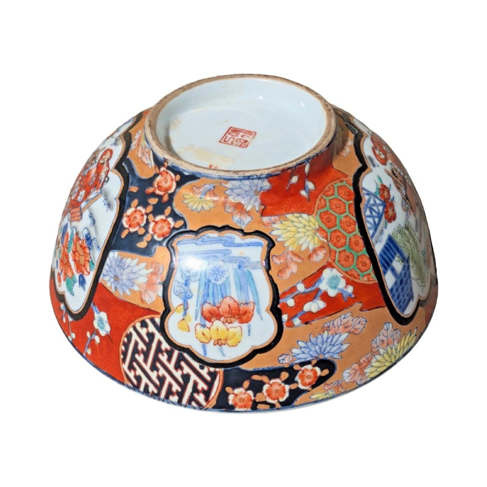 A deep round Japanese Imari porcelain bowl decorated with iron red, blue, green, and gold painted patterns featuring central figural cartouches and floral motifs. View VIII