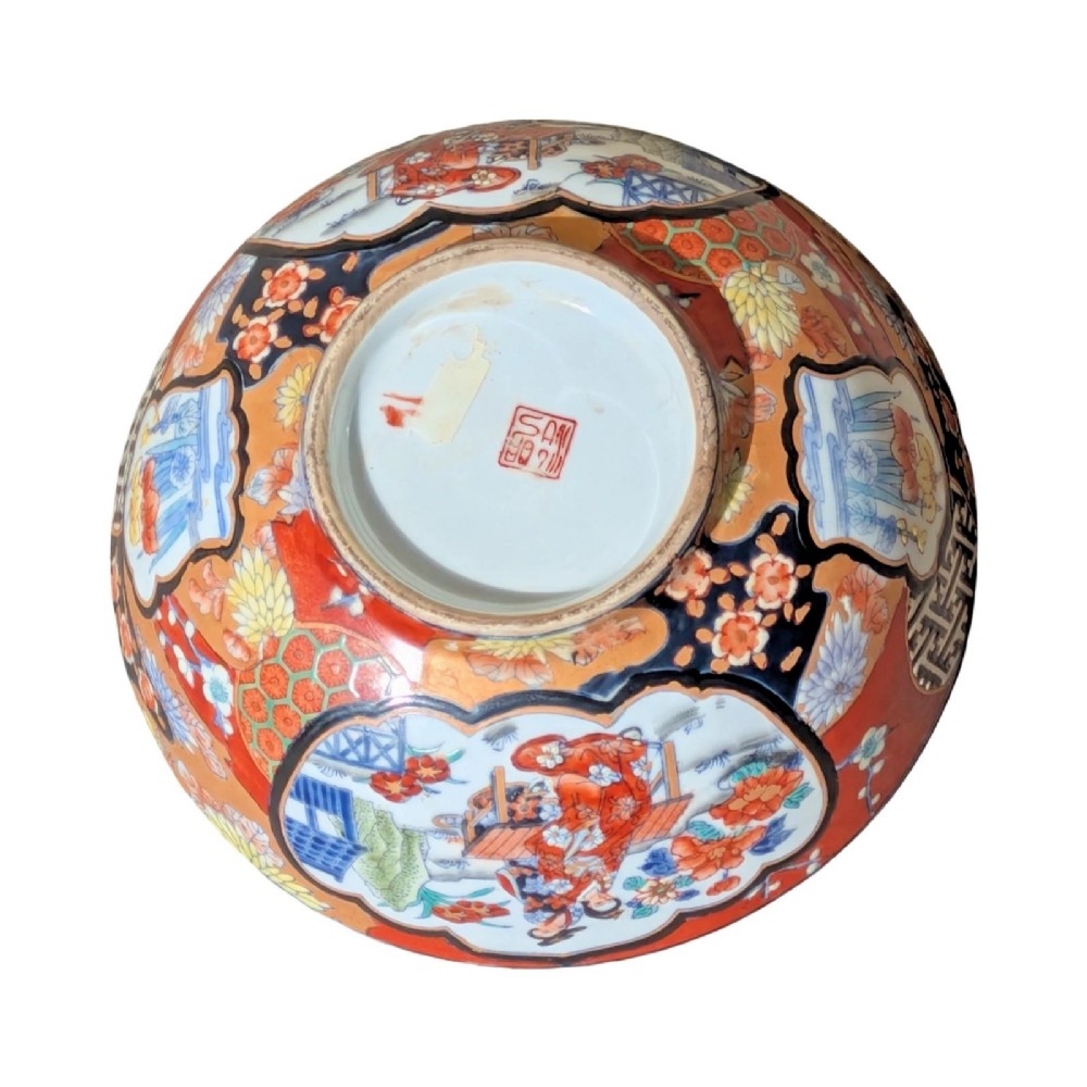 A deep round Japanese Imari porcelain bowl decorated with iron red, blue, green, and gold painted patterns featuring central figural cartouches and floral motifs. View IX