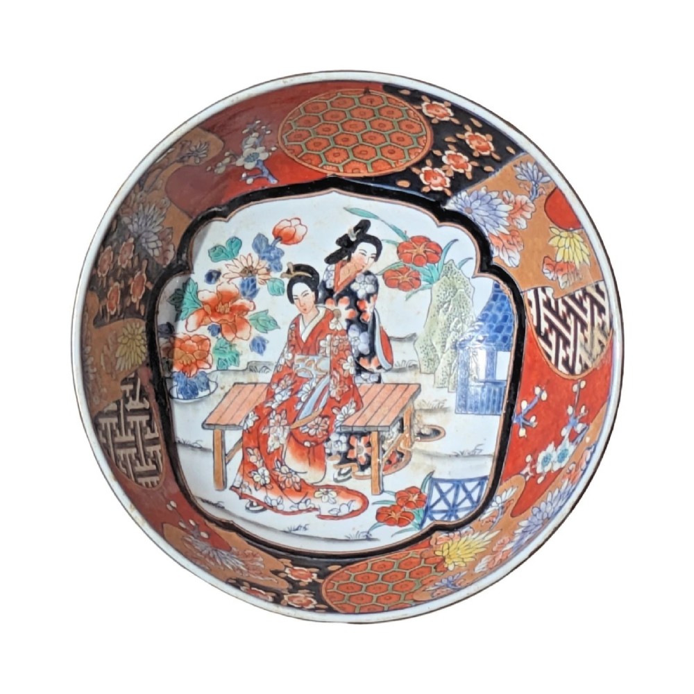 A deep round Japanese Imari porcelain bowl decorated with iron red, blue, green, and gold painted patterns featuring central figural cartouches and floral motifs. View XI