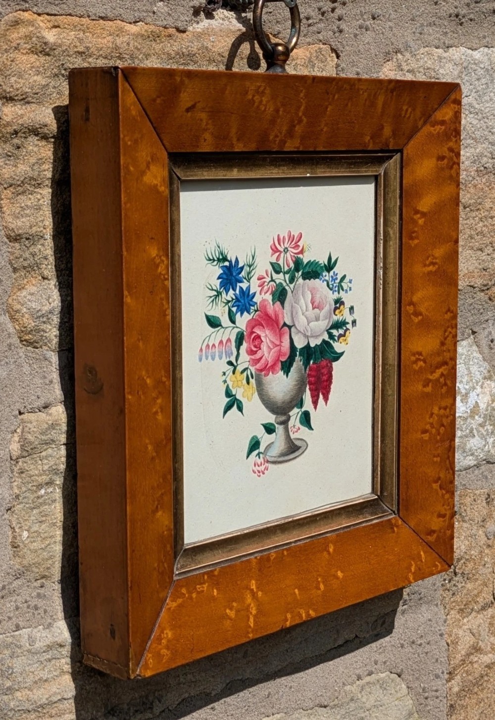 A framed Regency watercolour painting depicting a vibrant floral bouquet in an urn, set within a wide burr wood frame featuring a brass suspension ring. View II