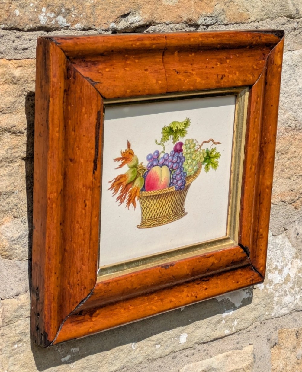 A nineteenth-century watercolour illustration depicting a woven basket filled with grapes, peaches, and hazelnuts, presented in a wide maple veneer frame with a gilded inner slip. View II