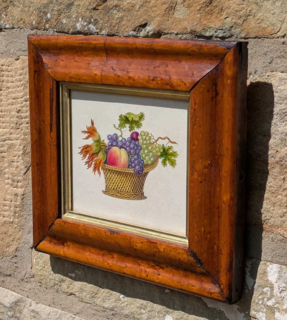 A nineteenth-century watercolour illustration depicting a woven basket filled with grapes, peaches, and hazelnuts, presented in a wide maple veneer frame with a gilded inner slip. View III